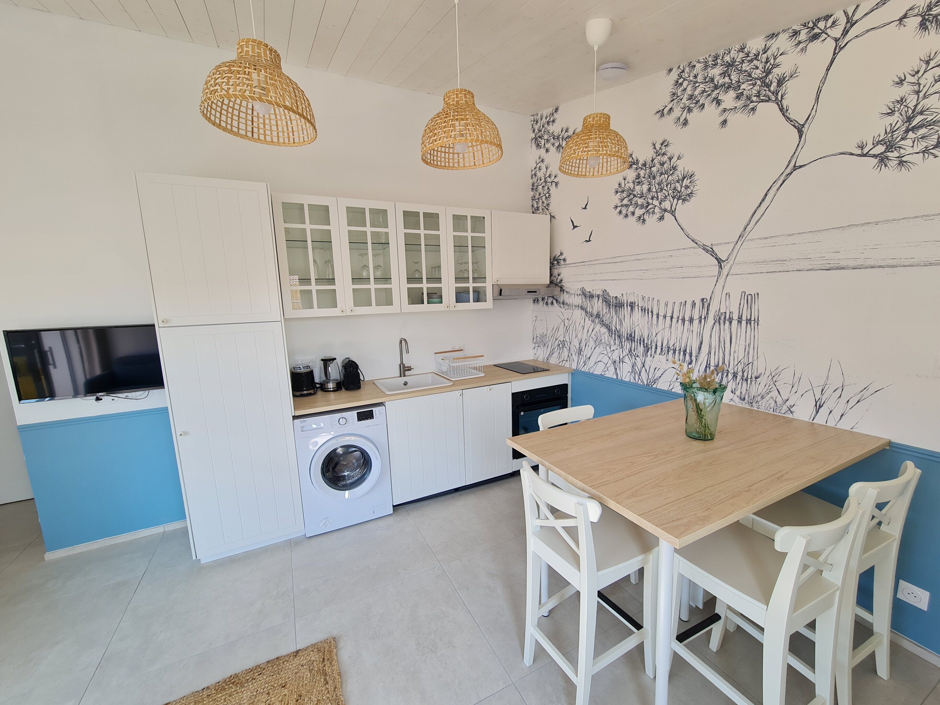Cozinha moderna com máquina de lavar, pia e área de jantar com mesa e cadeiras.