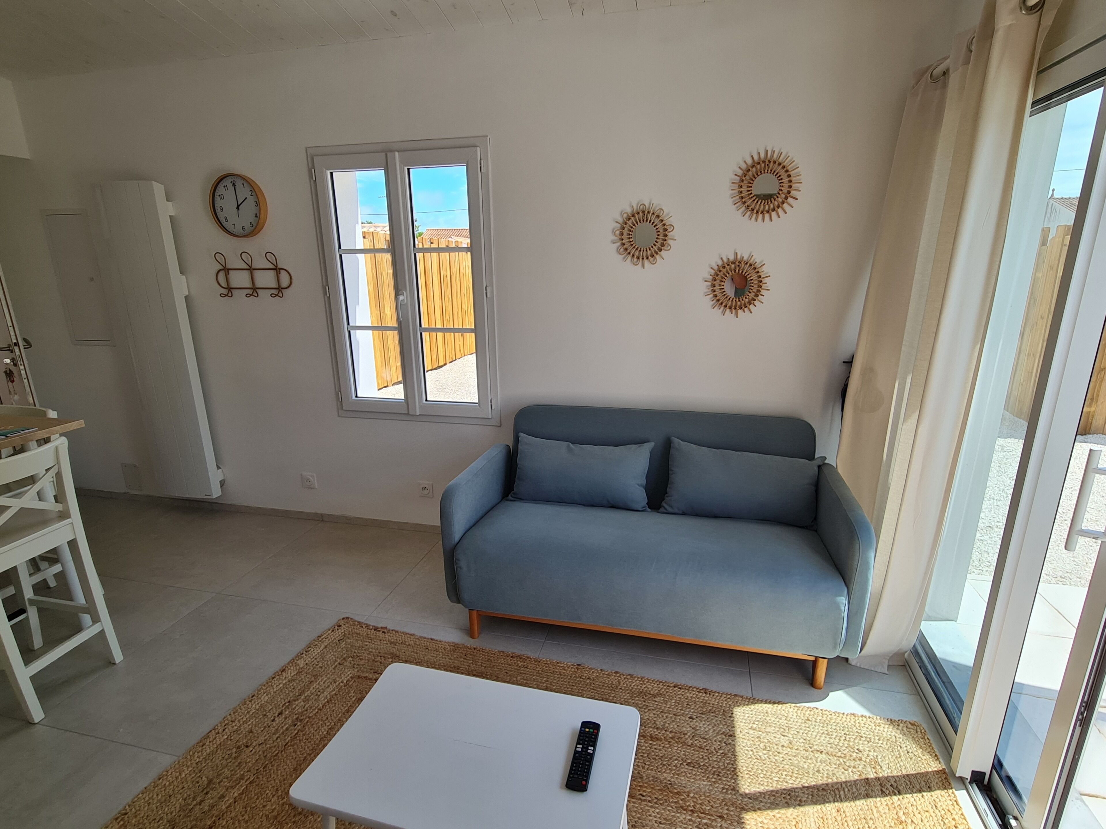 A living room with a blue sofa, a white table, a window, and wall decorations.