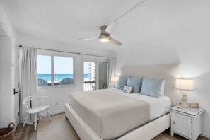 A bedroom with a bed, a nightstand, a chair, a ceiling fan, and a view of the ocean. - Beachfront PCB 2BR Condo w Pools, Tennis & Gulf Views + Free Attraction Tix! (Panama City Beach)