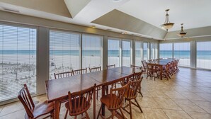A spacious dining area with large windows overlooking the beach, featuring wooden tables and chairs. - Beachfront PCB 2BR Condo w Pools, Tennis & Gulf Views + Free Attraction Tix! (Panama City Beach)