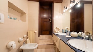 A bathroom with two sinks, a mirror, a towel rack, and a door.
