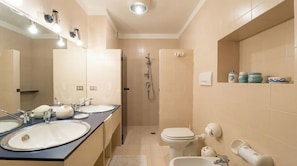 A bathroom with two sinks, a toilet, a shower, and a mirror.
