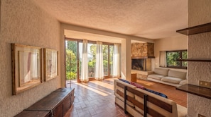 Un espacio habitable amplio con chimenea, ventanas grandes y un sofá.