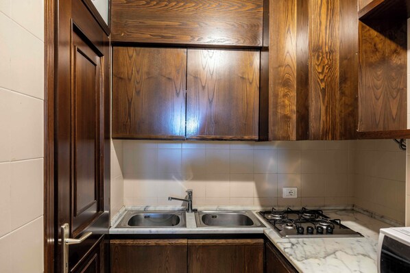 A kitchen with wooden cabinets, a double sink, and a gas stove.