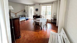 Una habitación con una mesa de comedor, sillas, un banco, un sofá y una ventana con cortinas.