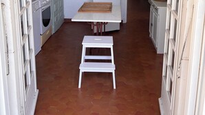 Una cocina estrecha con un refrigerador blanco, una mesita y un taburete.