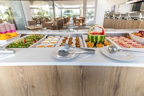 A buffet with various food items and utensils. - Pefkos Breeze Family Resort & Spa (Rhodes)