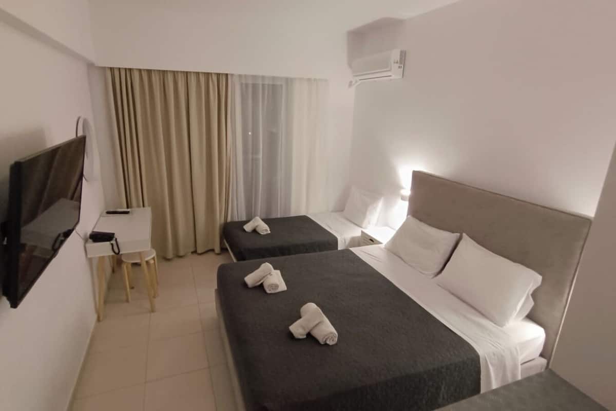 A hotel room with two beds, a TV, a desk, and a chair.