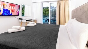 A hotel room with a large bed, a desk, a television, and a view of the outdoors. - Pefkos Breeze Family Resort & Spa (Rhodes)