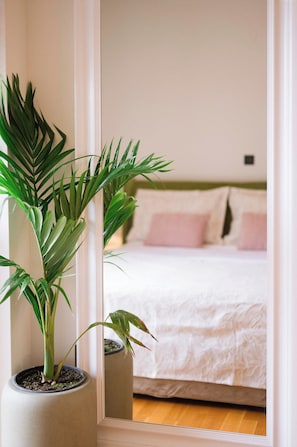 Ein Schlafzimmer mit einem Bett, Kissen und einer Topfpflanze.