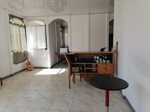 A room with a wooden table, a guitar, and a kitchenette area. - Auralivingcr (La Garita)