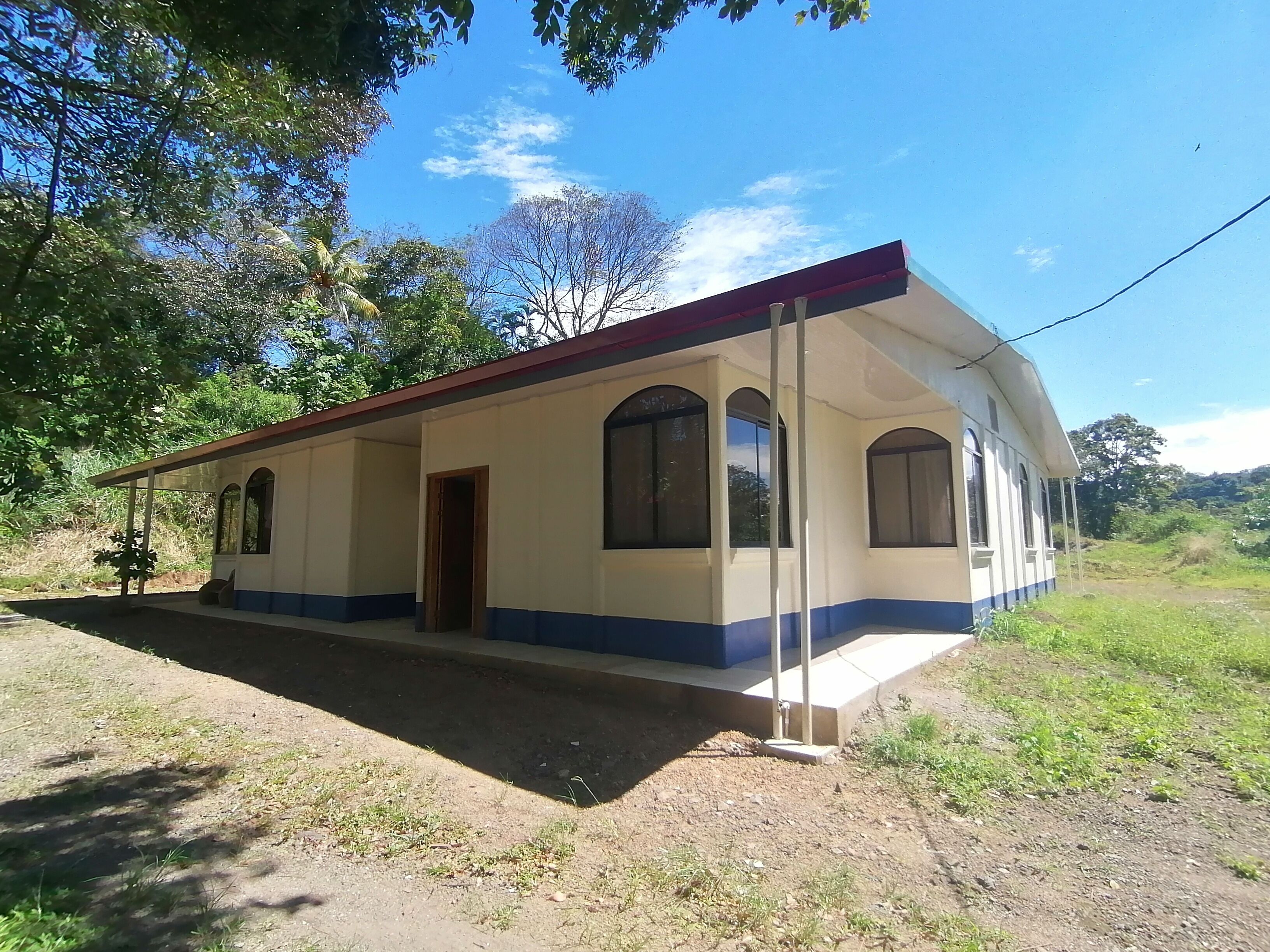 Um edifício térreo com telhado curvo, porta frontal e janelas amplas.