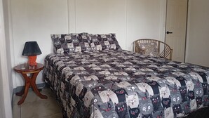 Una cama con colcha estampada, una mesita de noche con lámpara y una silla.