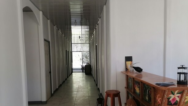 Un pasillo con una zona de bar de madera, taburetes y una vista a través de una ventana con barrotes.