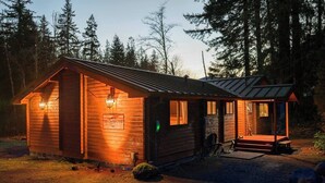 Eine Holzhütte mit Veranda, einem Schild und einem kleinen Vorgarten.