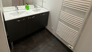 A bathroom with two sinks, a mirror, and a towel rack. - Duplex in the heart of Arras (Arras)