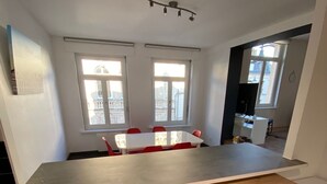 A kitchen with a wooden countertop, a dining table with red chairs, and two windows with a city view. - Duplex in the heart of Arras (Arras)