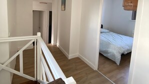 A staircase leading to a bedroom with a bed, a hanging light fixture, and a door leading to another room. - Duplex in the heart of Arras (Arras)