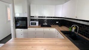 A modern kitchen with white cabinets, a black backsplash, and a wooden countertop. - Duplex in the heart of Arras (Arras)