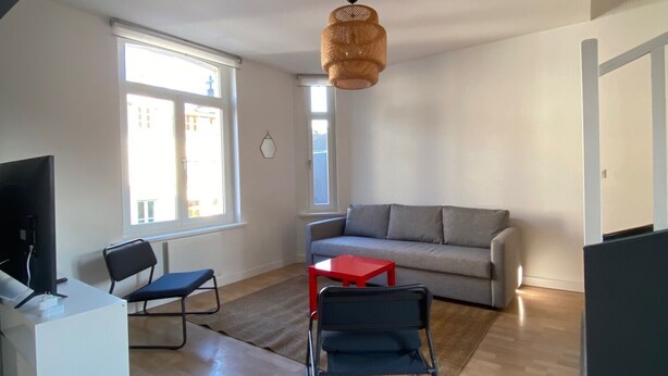 A spacious living area with a sofa, a dining table, and a TV. - Duplex in the heart of Arras (Arras)