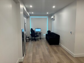 A modern office space with a desk, two chairs, a black sofa, and a computer monitor. - 2-bedroom apartment in gorgeous New York with fitness room and AC (New York)