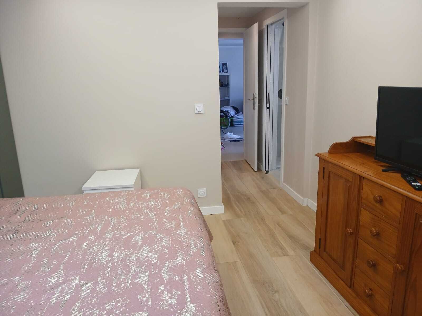A bedroom with a bed, a wooden dresser, and a television.