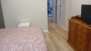 Ein Schlafzimmer mit einem Bett, einer Holzkommode und einem Fernseher.