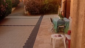 Eine Terrasse mit Tisch und Stühlen, ein Weg und ein Gebäude im Hintergrund.