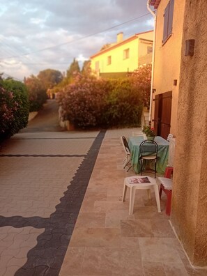 A patio area with a table and chairs, a pathway, and a building in the background.