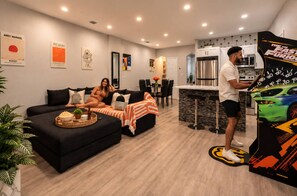 A modern living room with a sofa, a dining area, and a kitchen. - Arcade + Plunge Pool - Calle Ocho Near Brickell (Miami)