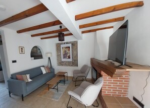 A living room with a sofa, a small table, a chair, a TV, and a fireplace.