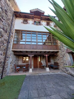 A two-story stone building with a balcony, wooden furniture, and a stone wall.