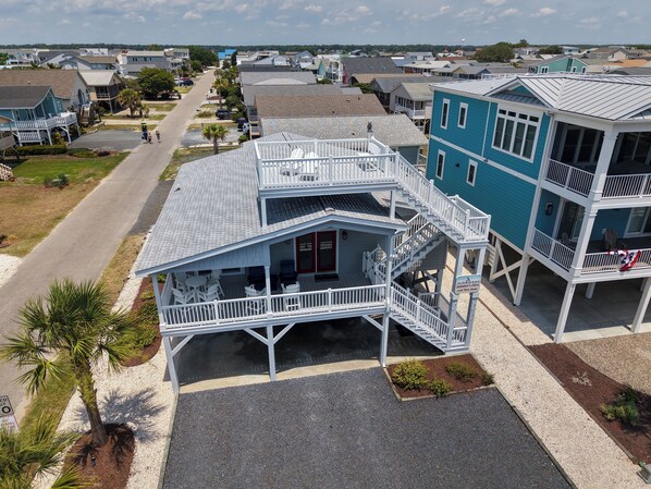 A beachfront property with a two-story building, a covered patio, and a view of the ocean. - Second Row Sunset Beach Island West    Coastal Escape 
Luxury Beach House (Sunset Beach)