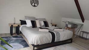Un dormitorio con cama, mesitas de noche, una obra de arte en la pared y un escritorio.