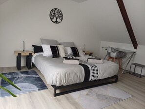 Ein Schlafzimmer mit Bett, Nachttischen, einem Wandbild und einem Schreibtisch.