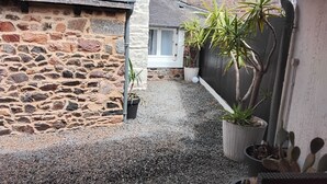 Un edificio de piedra con un camino de grava, plantas en macetas y un arreglo de cactus.