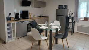 Una cocina moderna con comedor, que incluye una mesa de vidrio, sillas y un horno empotrado.