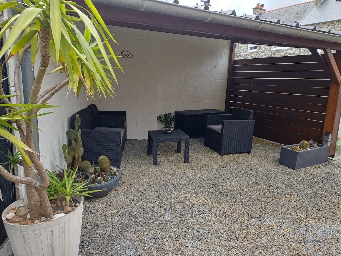 Un patio con una mesa y sillas, una planta en maceta y una exhibición de cactus.