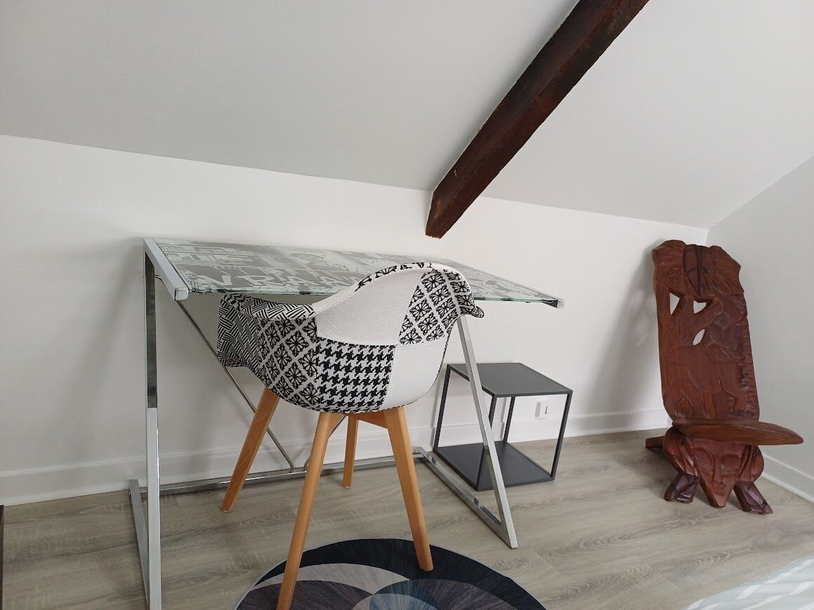 A room with a desk, chair, and a small side table.