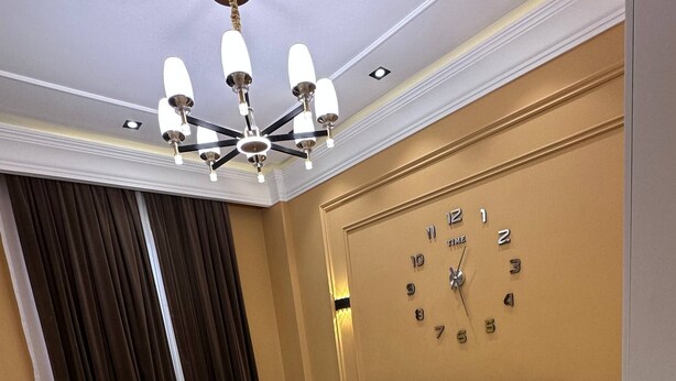 Habitación de hotel con cama, un reloj en la pared y una araña.