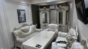 Un dormitorio lujoso con una cama grande, muebles ornamentados, una araña y un televisor montado en la pared.