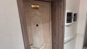 Una puerta de madera con un cartel de latón, un felpudo y una caja eléctrica fijada a la pared.