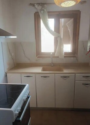 A kitchen with a stove, sink, and cabinets. - Serene 1-bedroom house with AC in charming Kallikrateia (Kallikrateia)