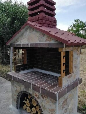 A stone-built outdoor grill with a tiled floor and a chimney. - Serene 1-bedroom house with AC in charming Kallikrateia (Kallikrateia)