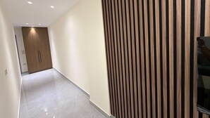 Un pasillo con pared de paneles de madera, una puerta al final y suelo de baldosas.