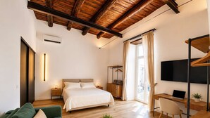 A modern hotel room with a bed, a desk, a television, and a sofa. - Penthouse Napoli Terrace-Dante Rooftop (Naples)