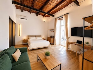 Ein modernes Hotelzimmer mit Bett, Schreibtisch, Fernseher und einer Sitzecke.