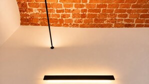 Eine moderne Deckenleuchte mit schwarzem Fuß und einer horizontalen Lichtleiste, montiert an einer schlichten weißen Decke.