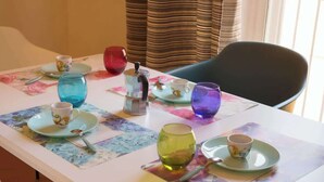 A table set with various glassware and plates, a coffee pot, and a chair. - Appartamento spazioso Napoli centro con terrazzo (Naples)