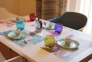 Ein Tisch ist gedeckt mit verschiedenen Gläsern und Tellern, einer Kaffeekanne und einem Stuhl.